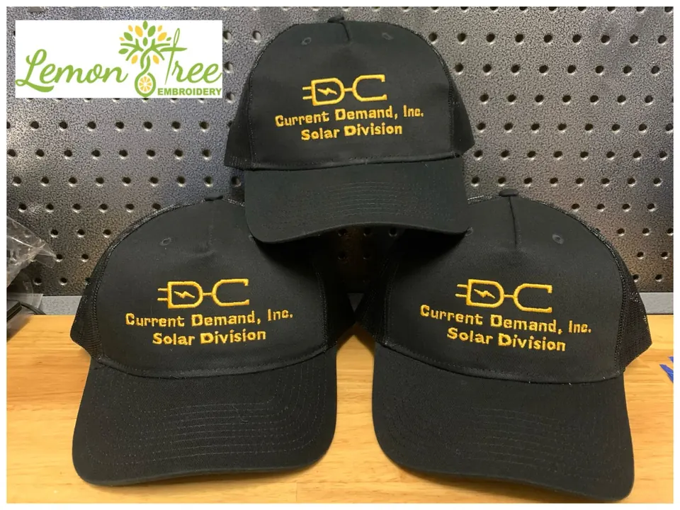 Three black hats embroidered with the Current Demand, Inc. Solar Division logo in gold