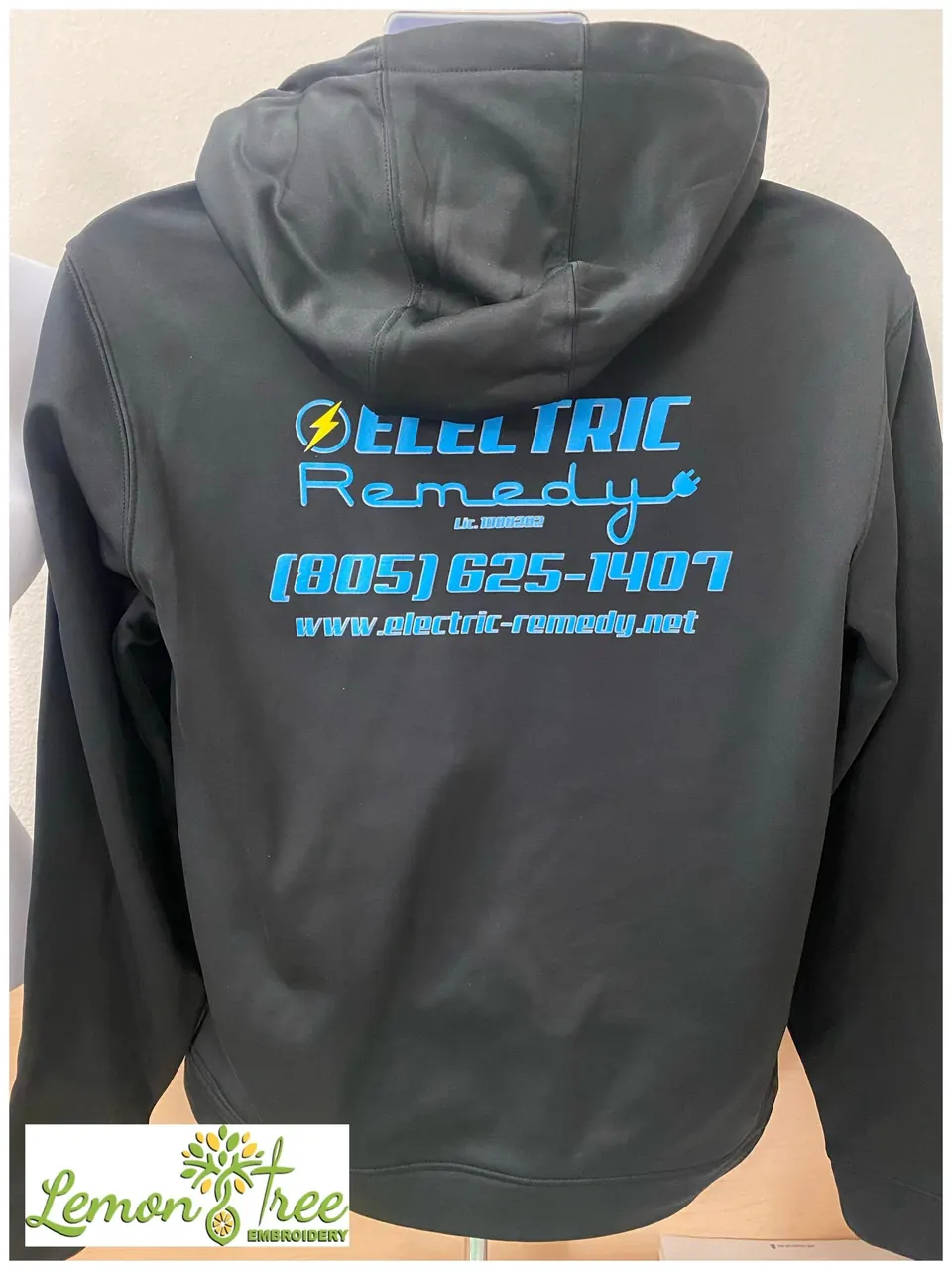 Black hoodie with the Electric Remedy logo printed in bright blue on the back