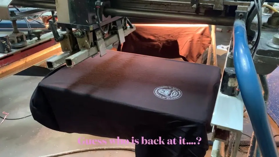 Automatic screen printing press printing a logo on a black tee