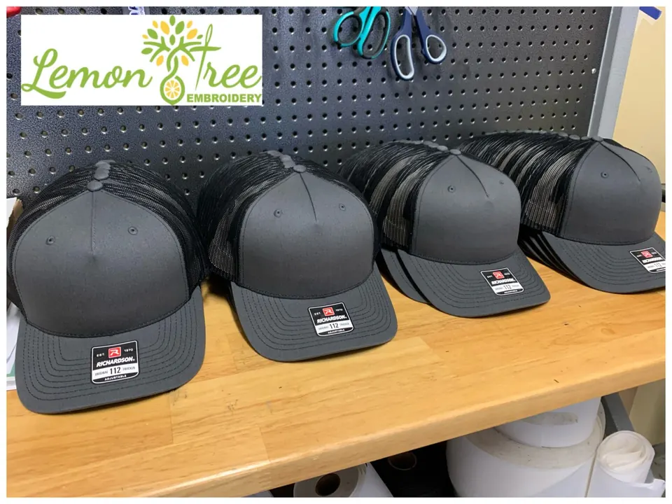 Rows of gray and black trucker hats lined up on the shop bench